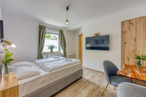 a bedroom with a large bed and a chair at VILA LISJAK - Apartments in Podčetrtek