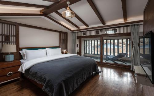 a bedroom with a large bed and a large window at Lijiang Gemmer Hotel in Lijiang