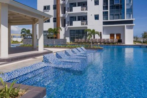 a swimming pool with blue chairs in front of a building at Mactan Newtown Beach Condo in Mactan