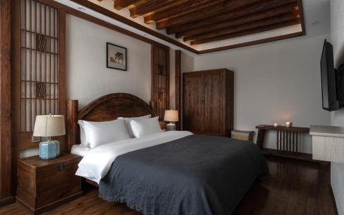 a bedroom with a large bed and a tv at Lijiang Gemmer Hotel in Lijiang