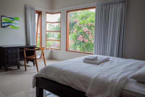 a bedroom with a bed and a desk and a window at Terrace Mumbul in Nusa Dua