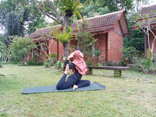 a woman doing a yoga pose in the grass at Villa Mak Cik in Yogyakarta