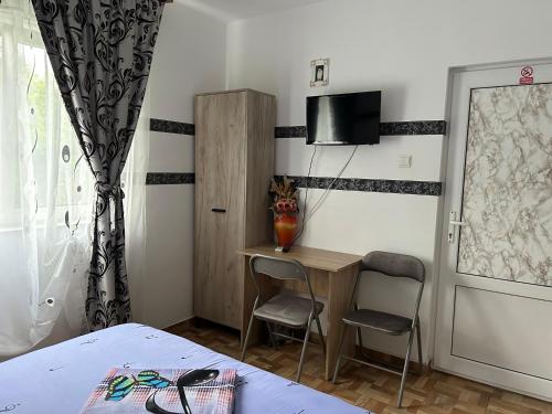 a bedroom with a desk and a tv on the wall at Vila MariCris in Tuzla