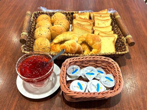 a table with two baskets of bread and a basket of jam at Green Rich Hotel & Capsule Naha - Artificial hot spring Futamata Yunohana in Naha