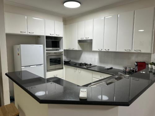 a kitchen with white cabinets and a black counter top at Resort Style 2BR Apt in Pyrmont Next to Darling Harbour in Sydney