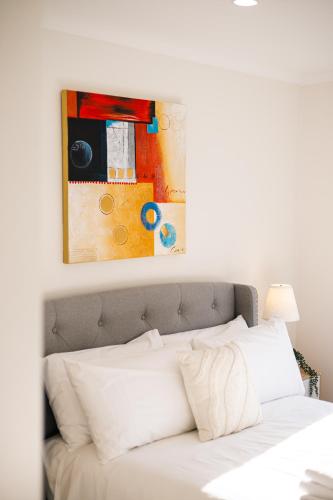 a bedroom with a white bed with a painting above it at StayAU Family Group 6BR Oasis Sanctuary Lakeview in Point Cook