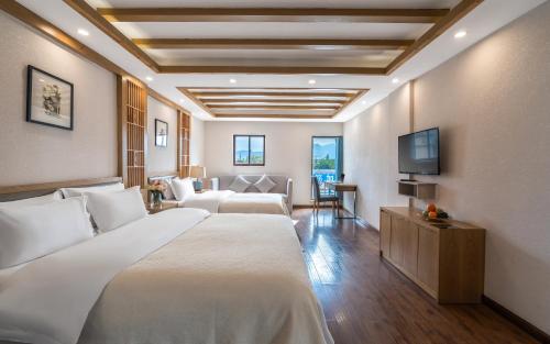 um quarto de hotel com uma cama e uma televisão de ecrã plano em Lijiang Gemmer Hotel em Lijiang