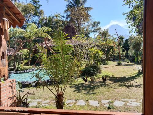 a garden with palm trees and a swimming pool at Villa Mak Cik in Yogyakarta
