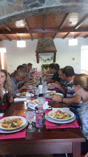 a group of people sitting at a long table eating food at Quinta das Colmeias in Lanção