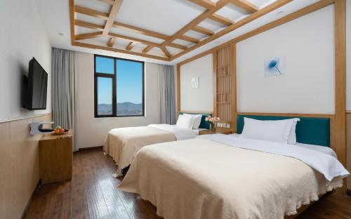 a hotel room with two beds and a flat screen tv at Lijiang Gemmer Hotel in Lijiang
