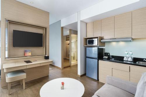 a living room with a couch and a kitchen with a tv at Swiss-Belinn Modern Cikande in Serang