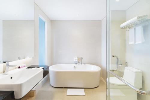 a white bathroom with a tub and a sink at Swiss-Belinn Modern Cikande in Serang