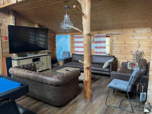 een woonkamer met banken en een flatscreen-tv bij Luxury Holiday Home with Private Lake in Vehmaa