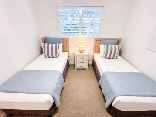two twin beds in a room with a window at Regatta Noosa in Noosaville