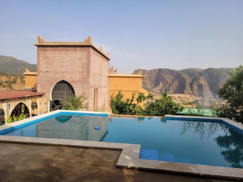 une piscine en face d'un bâtiment avec des montagnes en arrière-plan dans l'établissement Chambre d'hôtes aya, à Ouzoud