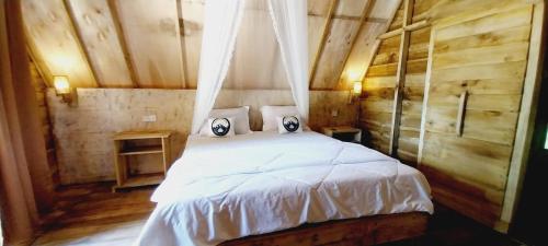 - une chambre avec un lit doté de draps et d'oreillers blancs dans l'établissement Girang Rinjani Bungalows, à Tetebatu