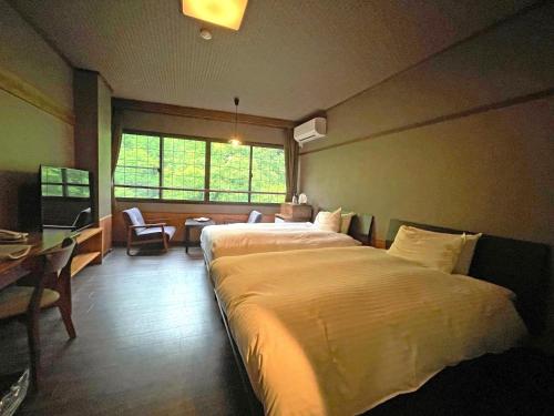 会津若松市にあるくつろぎ宿　新滝の大きなベッドとデスクが備わるホテルルームです。