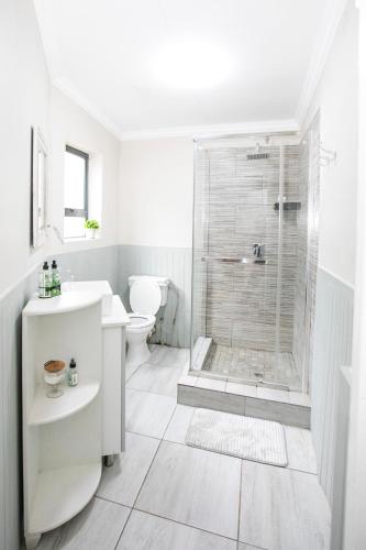 a white bathroom with a shower and a toilet at Buchan's corner Unit 1 in Hartbeespoort