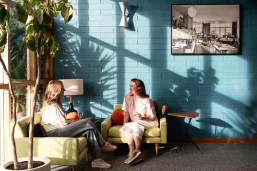 Dos mujeres sentadas en sillas en una habitación con una pared azul en Riverfront Motel & Villas en Hobart
