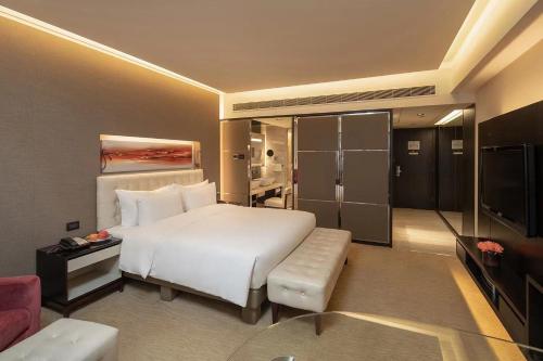 a bedroom with a large white bed and a living room at Furama Hotel Dalian in Dalian