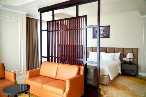 a hotel room with a bed and a chair at La Vela Hue Hotel in Hue