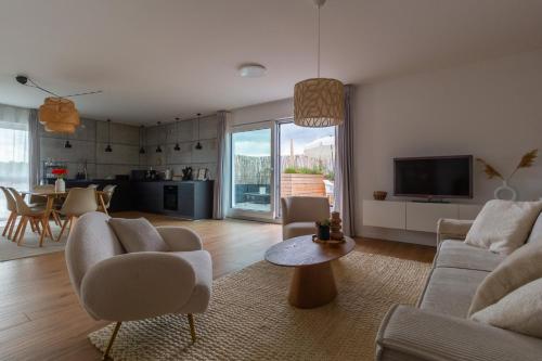 a living room with a couch and chairs and a tv at Penthouse-Ferienwohnung Wolfsburg mit Dachterrasse WLAN Smart-TV überdachter Parkplatz Wallbox in Wolfsburg