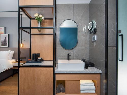 a bathroom with a sink and a mirror at Country Inn & Suite by Radisson, Tianjin Wuqing Development Zone Wanda Plaza in Wuqing