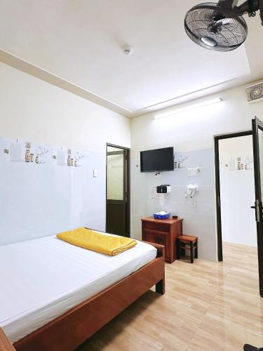 a white bedroom with a bed and a tv on the wall at Nhà Nghỉ Thành Duy in Quang Ngai