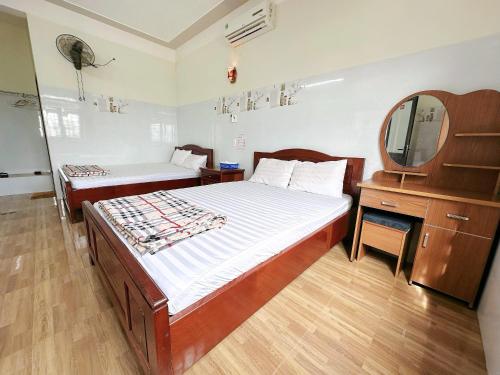 a bedroom with a bed and a dresser and a mirror at Nhà Nghỉ Thành Duy in Quang Ngai