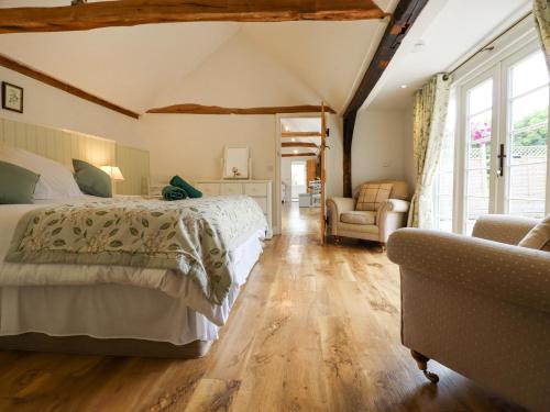 une chambre avec un grand lit et une chaise dans l'établissement Oast Cottage, à Maidstone
