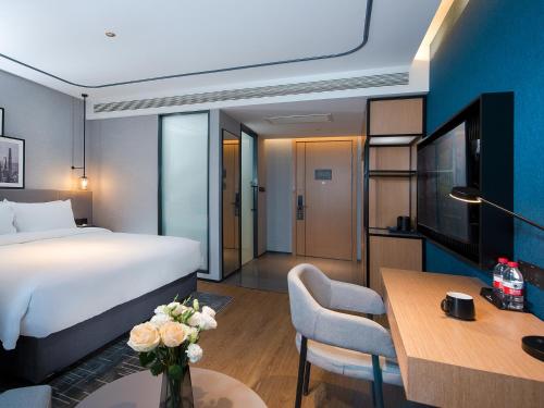 a hotel room with a bed and a dining room at Country Inn & Suite by Radisson, Tianjin Wuqing Development Zone Wanda Plaza in Wuqing
