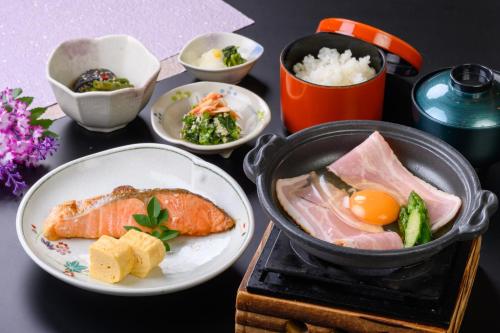 a table with a plate of food and bowls of food at Hotel Green Park Suzuka in Suzuka