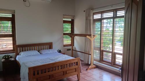 a bedroom with a bed in a room with windows at Mountain View Villa Vacation Rental in Idukki