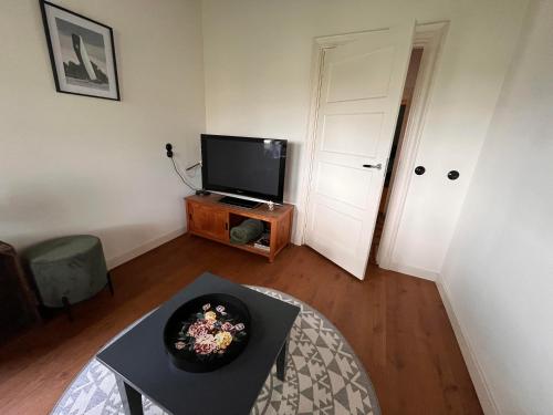 a living room with a tv and a table at BnB Alde Hiemen Friesland in Terwispel