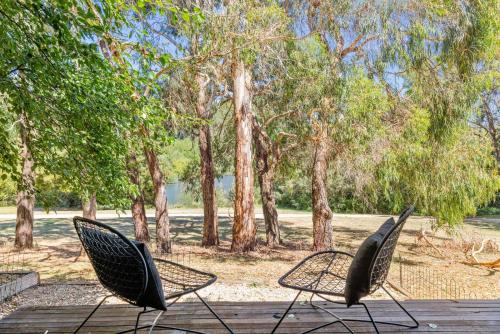 two chairs sitting on a wooden deck with trees at Romantic Lakefront Luxury - Spa Bath, Fireplace, King Bed in Daylesford
