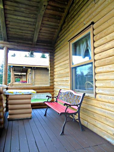a bench sitting on a porch of a cabin at Cajun Cedar Log Cottages in Margaree Forks