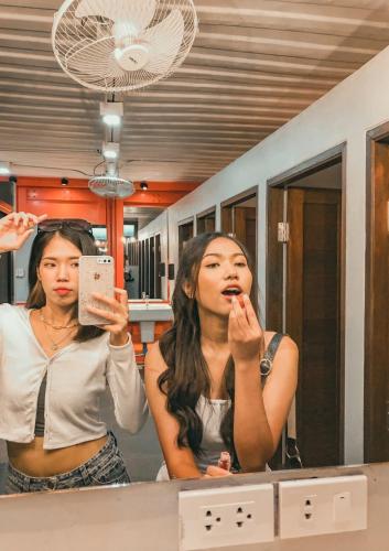 a woman brushing her teeth in front of a mirror at Ubox samui hostel & Bungalow - Chaweng beach in Chaweng