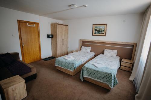 ein Hotelzimmer mit 2 Betten und einem Sofa in der Unterkunft Gros Hotel - Leskovac in Leskovac