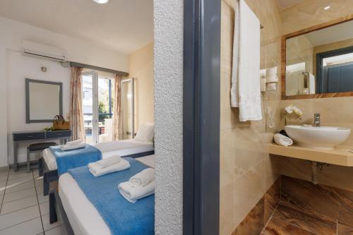 a hotel room with two beds and a sink at Agrabella Hotel in Hersonissos