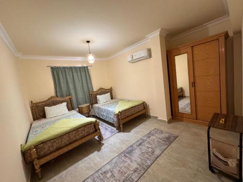 a bedroom with two beds and a mirror at Cozy villa in Stella Heights 3 bed rooms - North Coast فيلا ستيلا هايتس الساحل الشمالي - سيدي عبدالرحمن in El Alamein
