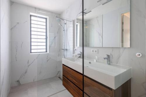 a white bathroom with a sink and a shower at Two Tides Luxury in Blue Bay