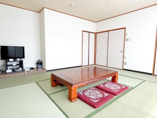 a living room with a wooden table and two red cushions at HOTEL　KAMO in Saijō-chō