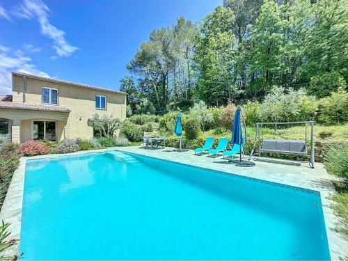 - une piscine avec 2 chaises bleues et des parasols dans l'établissement VillaNorah, à Le Rouret