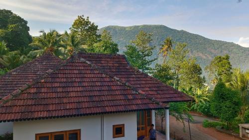 a house with a roof with a mountain in the background at Mountain View Villa Vacation Rental in Idukki