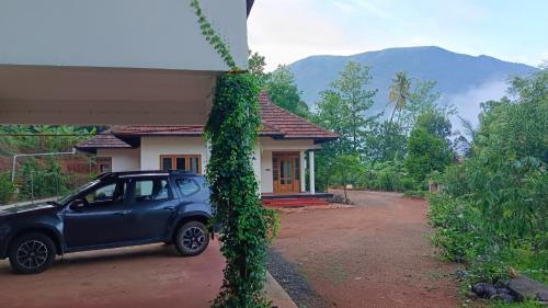 a small blue car parked in front of a house at Mountain View Villa Vacation Rental in Idukki