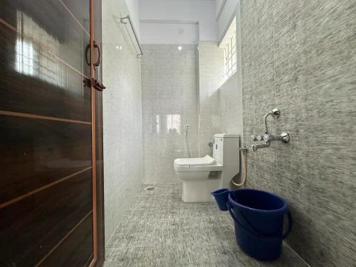 a bathroom with a toilet and a blue bucket at Cozy Room 1Bhk with Lift 202 in Bengaluru