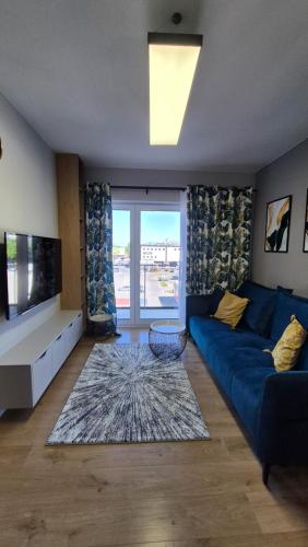 a living room with a blue couch and a large window at Sweet Home Grabieniec Apartment in Łódź