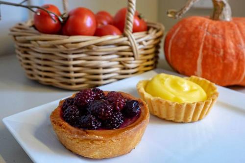 a plate with a cupcake with fruit on it and a basket of tomatoes at Battery Point Village - Stunning Large Home in Hobart