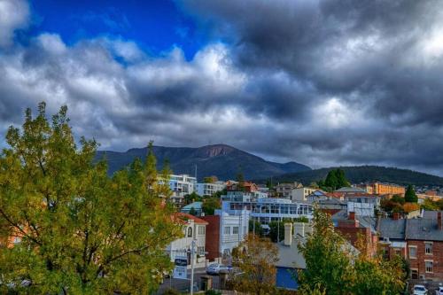 a city with trees and buildings under a cloudy sky at Battery Point Village - Stunning Large Home in Hobart