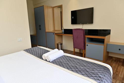 a hotel room with a bed with towels on it at HOMETOWN Sharu's Inn A Luxury Hotel in Chikmagalūr